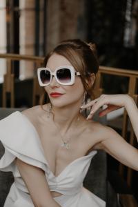 Stilvolles Brautportrait mit weißer Sonnenbrille und Off-Shoulder-Kleid, Luxushochzeit Berlin – Spreejuwel Hochzeiten