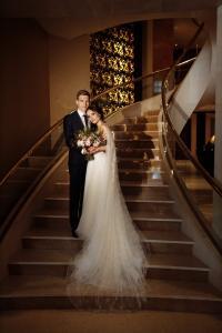 Brautpaar auf eleganter Treppe in warmem Licht, Schlosshochzeit Berlin Brandenburg – Spreejuwel Hochzeiten