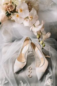 Weiße Brautschuhe mit Ringen und Blüten auf Brautschleier, Hochzeitsdetails Berlin – Spreejuwel Hochzeiten