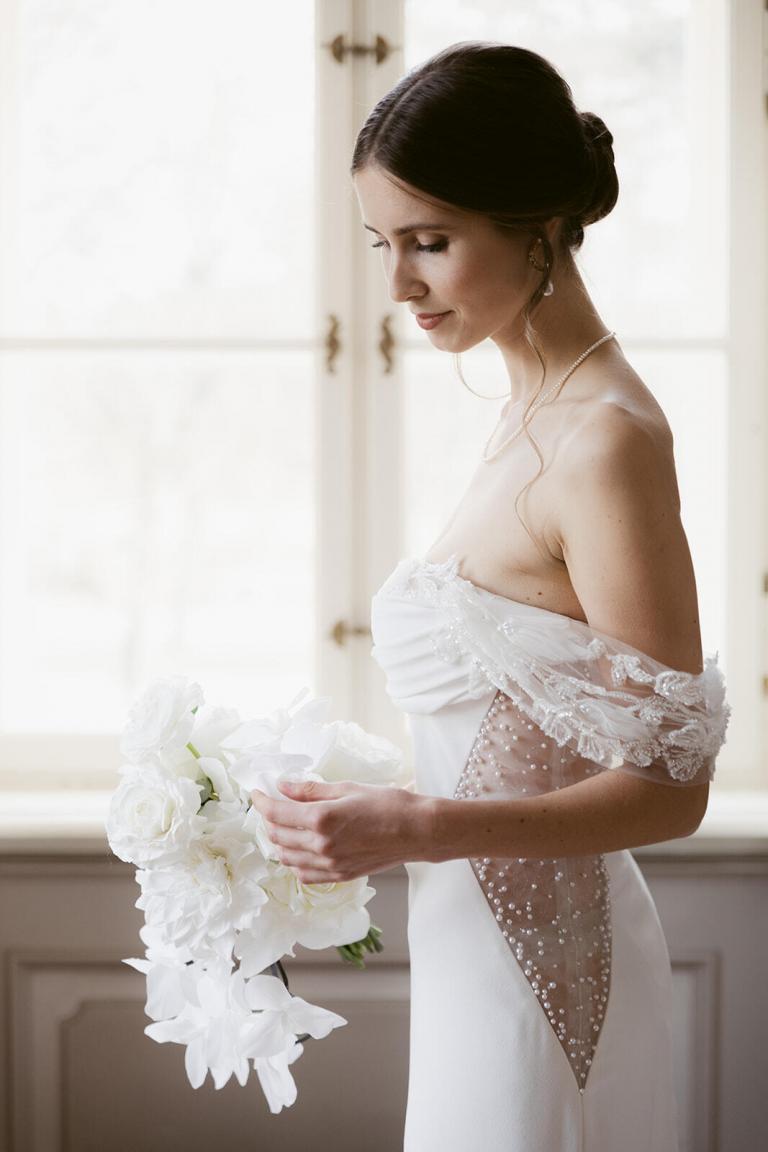 Braut im weißen Spitzenkleid am Fenster, Hochzeit Berlin Brandenburg – Spreejuwel Hochzeiten