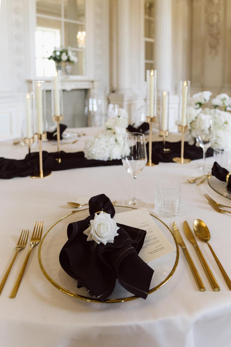 Festlich gedeckter Hochzeitstisch mit goldenem Besteck und schwarzen Servietten im Schloss Friedrichsfelde Berlin – Spreejuwel Hochzeiten
