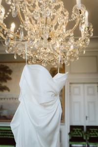 Braut berührt Kristallkronleuchter im Schloss Friedrichsfelde Berlin, märchenhafte Schlosshochzeit – Spreejuwel Hochzeiten