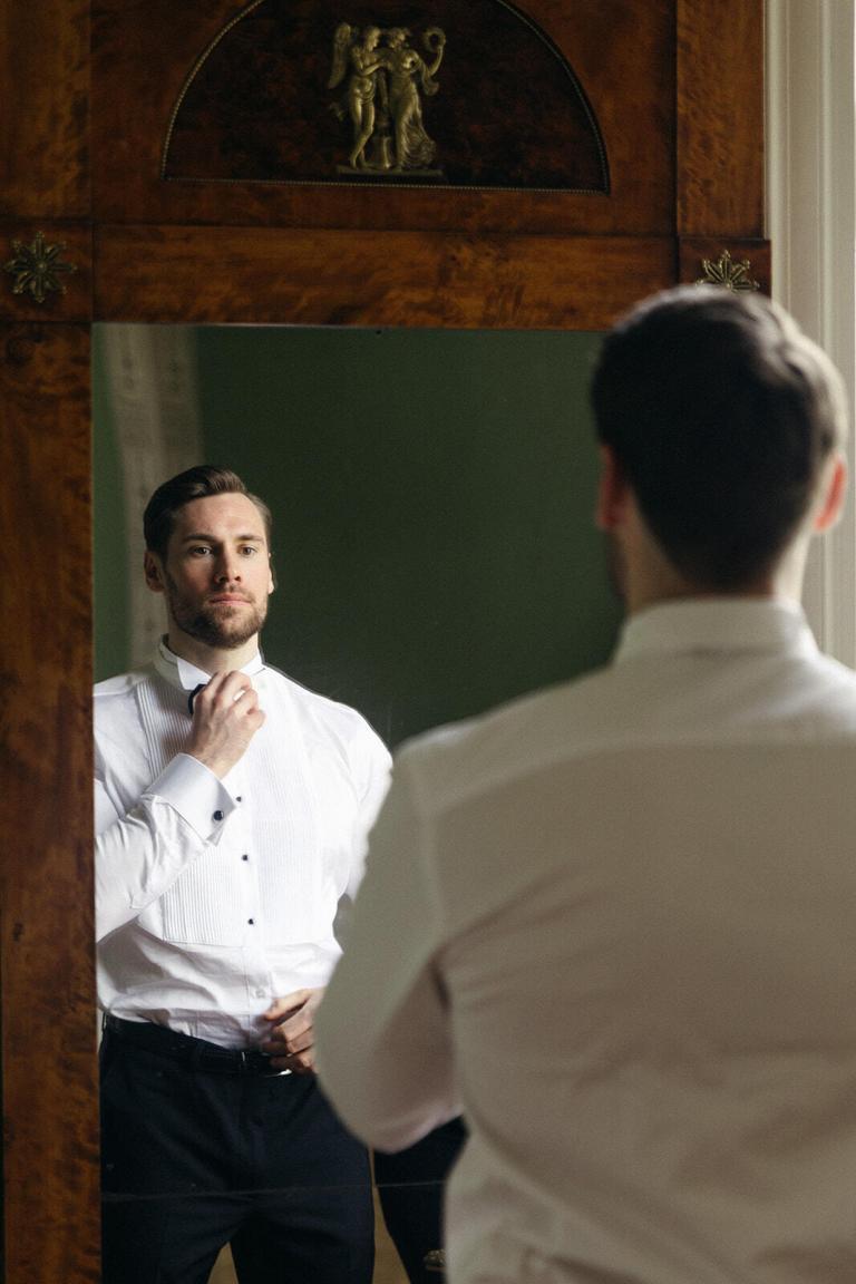 Bräutigam beim Getting Ready vor dem Spiegel im Schloss Friedrichsfelde Berlin – Spreejuwel Hochzeiten