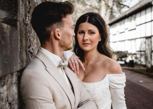 Inniges Brautpaar-Portrait vor Steinmauer im Gräflichen Park Bad Driburg, exklusive Hochzeitsplanung – Spreejuwel Hochzeiten