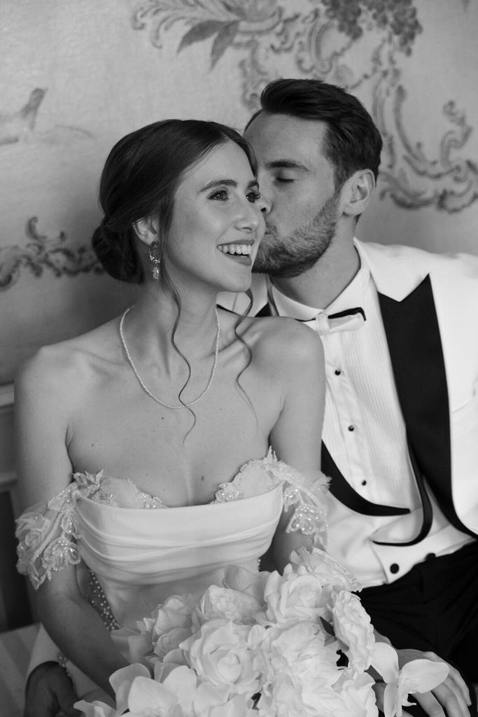 Brautpaar sitzt eng beieinander schwarz-weiß im Schloss Friedrichsfelde Berlin, romantische Hochzeit – Spreejuwel Hochzeiten