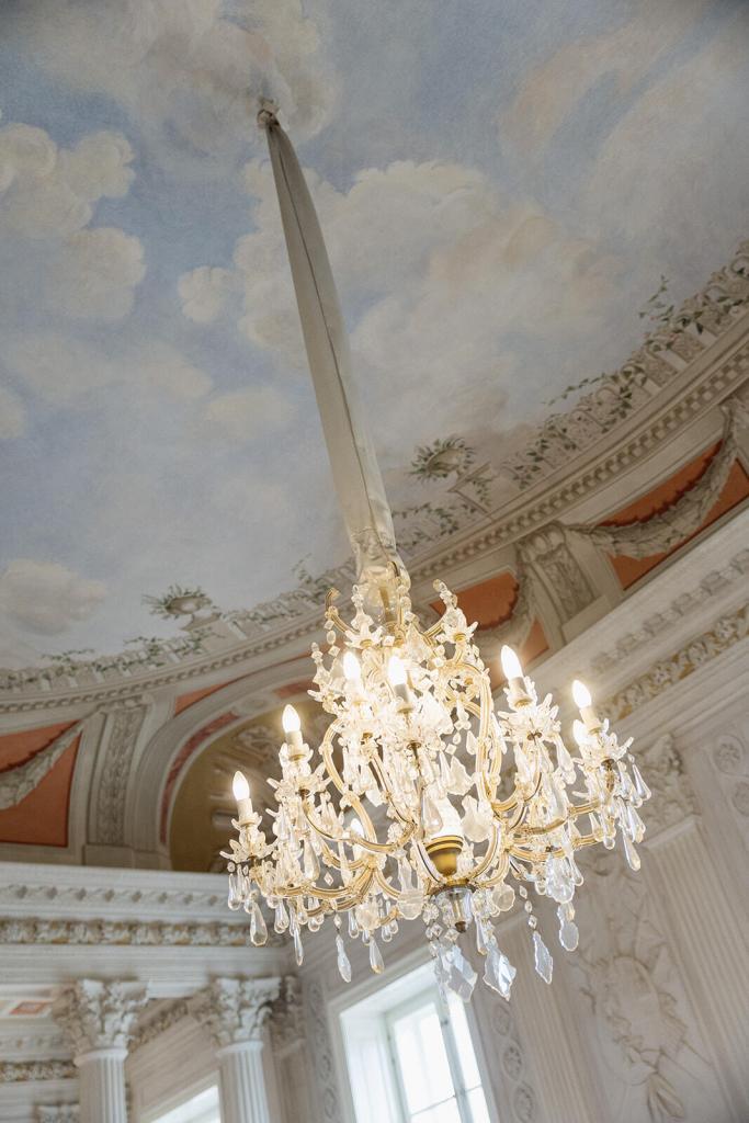 Prachtvoller Kristallkronleuchter vor bemalter Decke im Schloss Friedrichsfelde Berlin, märchenhafte Hochzeitslocation – Spreejuwel Hochzeiten