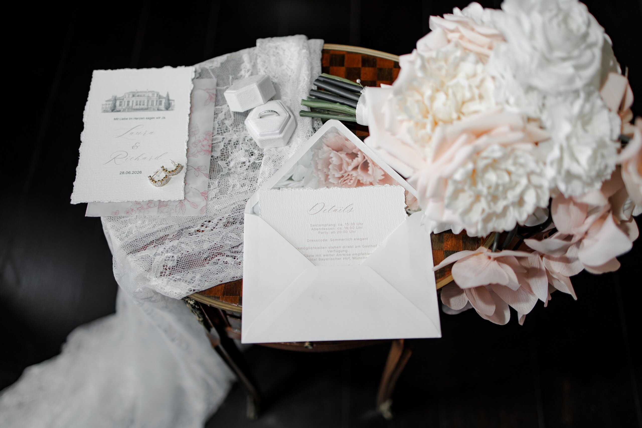 Edle Hochzeitspapeterie mit Einladungskarte, Details-Karte und Büttenrand, dazu Ohrringe, Ringschachtel und zartrosa Rosen auf Vintage-Beistelltisch, Hochzeit in der Villa Aurea in Potsdam