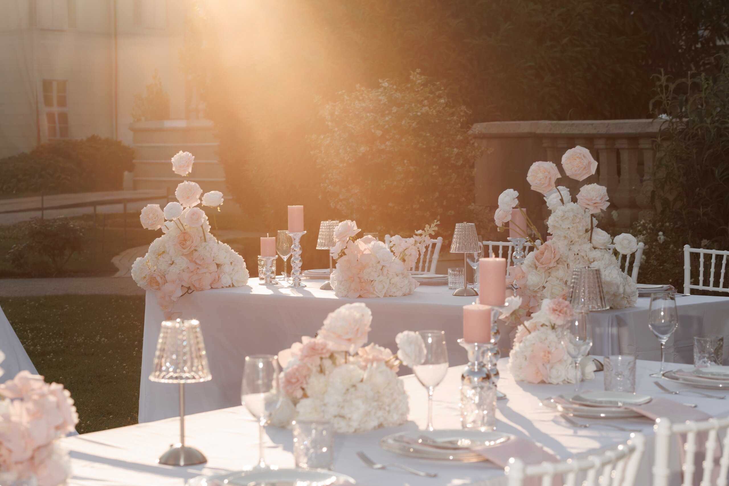 Festlich gedeckte Hochzeitstafel mit üppigen Rosen und Hortensien in Creme und Rosé, Kerzen und Kristallgläsern im Abendlicht, Hochzeit in der Villa Aurea in Potsdam