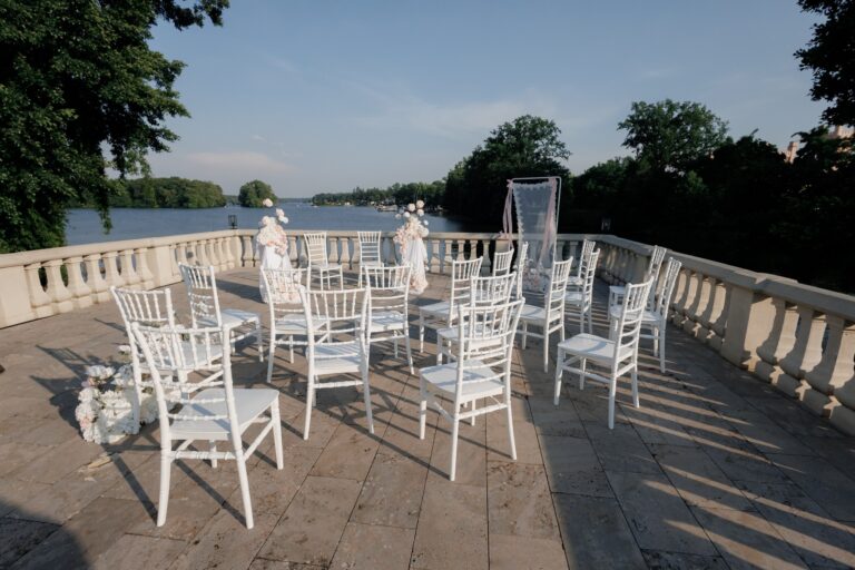 Weiße Stuhlreihen für eine freie Trauung auf einer Terrasse mit Seeblick — Zeremonie-Aufbau in Brandenburg