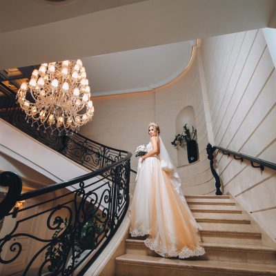 Braut auf Hoteltreppe mit Kronleuchter